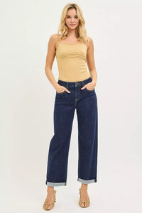 Woman wearing a beige strapless top and blue jeans on a white background