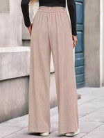 Person wearing beige wide-leg pants and a black top on a city street.