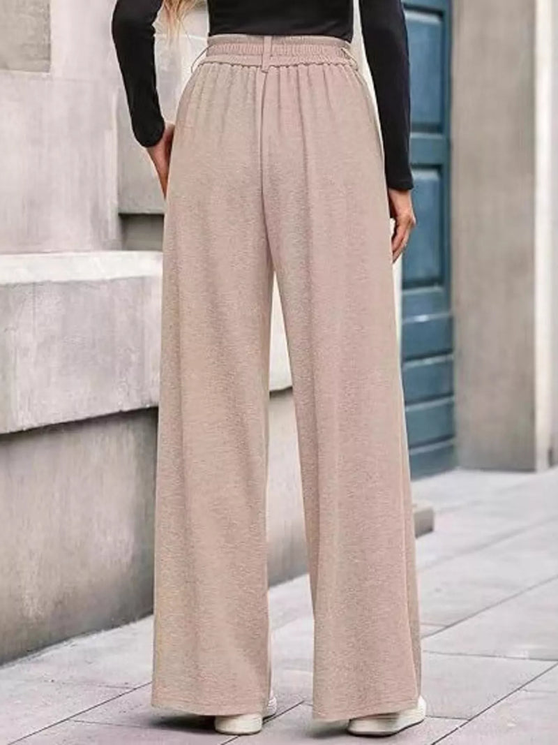 Person wearing beige wide-leg pants and a black top on a city street.