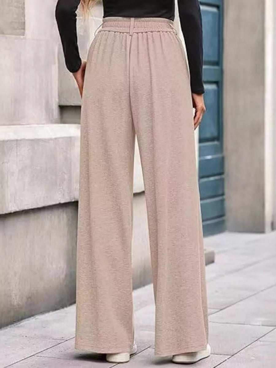 Person wearing beige wide-leg pants and a black top on a city street.