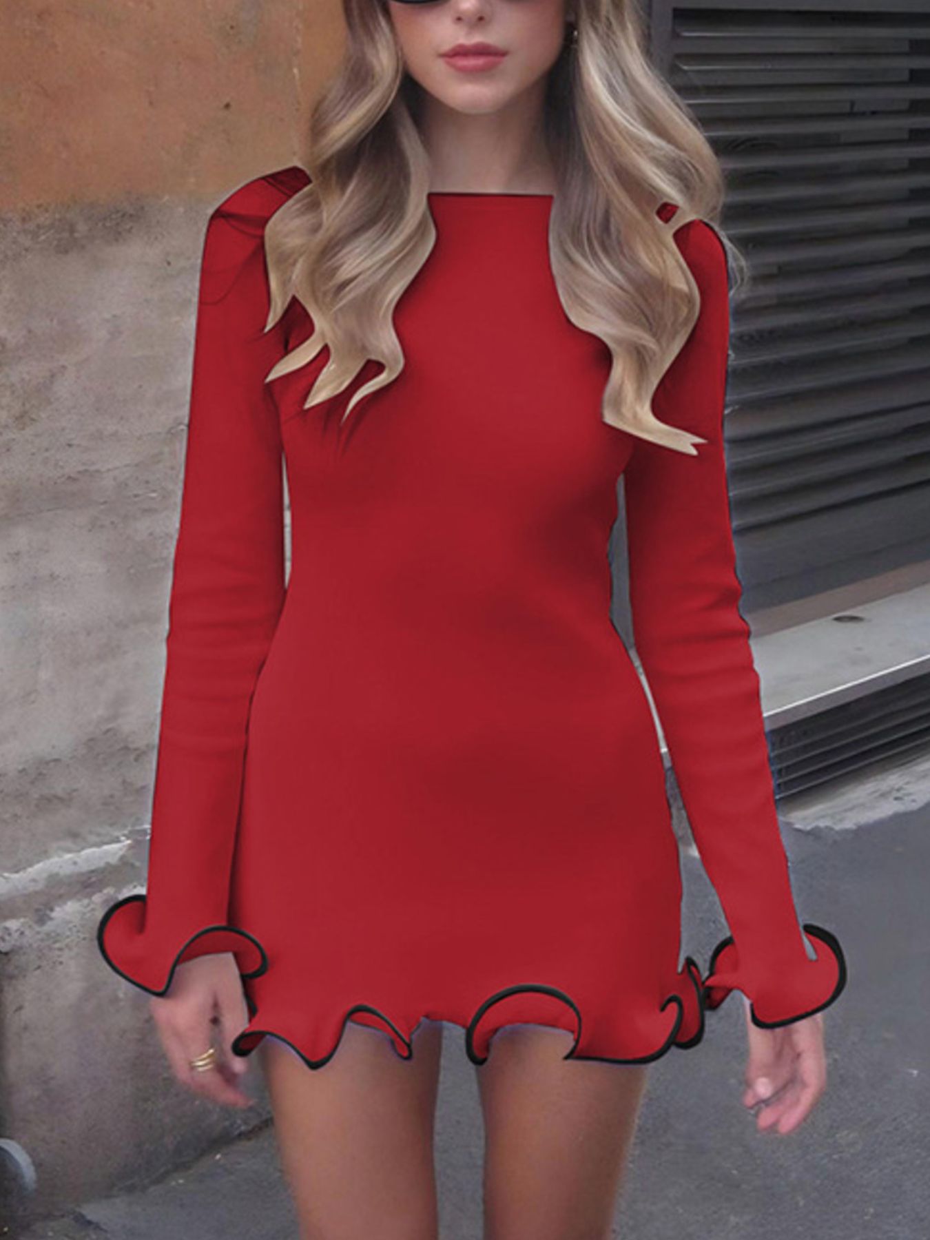 Woman wearing a red dress with long sleeves and ruffled hem on a street.