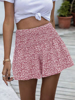 Person wearing a white top and pink floral skirt with a blurred background
