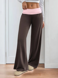 Person wearing brown wide-leg pants with a pink waistband against a white background