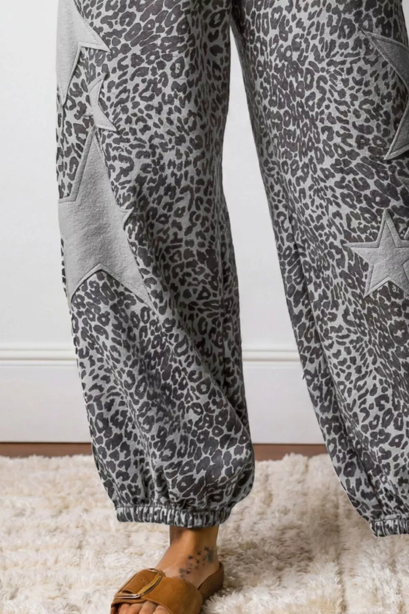 Leopard print pants with star details worn by a person on a white background