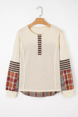 Beige sweater with plaid sleeves on a wooden hanger against a white background