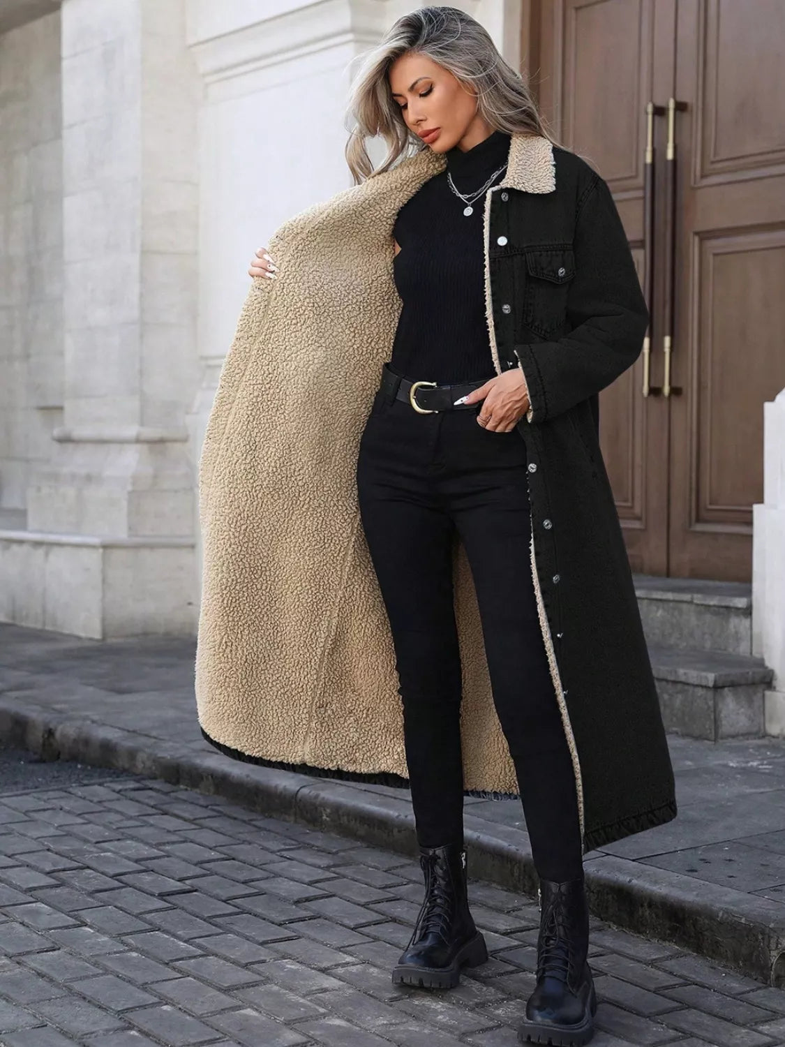 Woman wearing a black coat with beige lining on a city street.