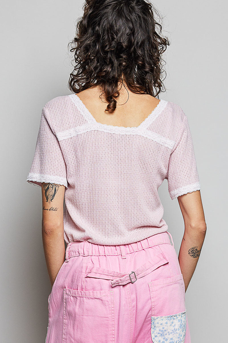 Person wearing a pink textured top and pink pants with a gray background