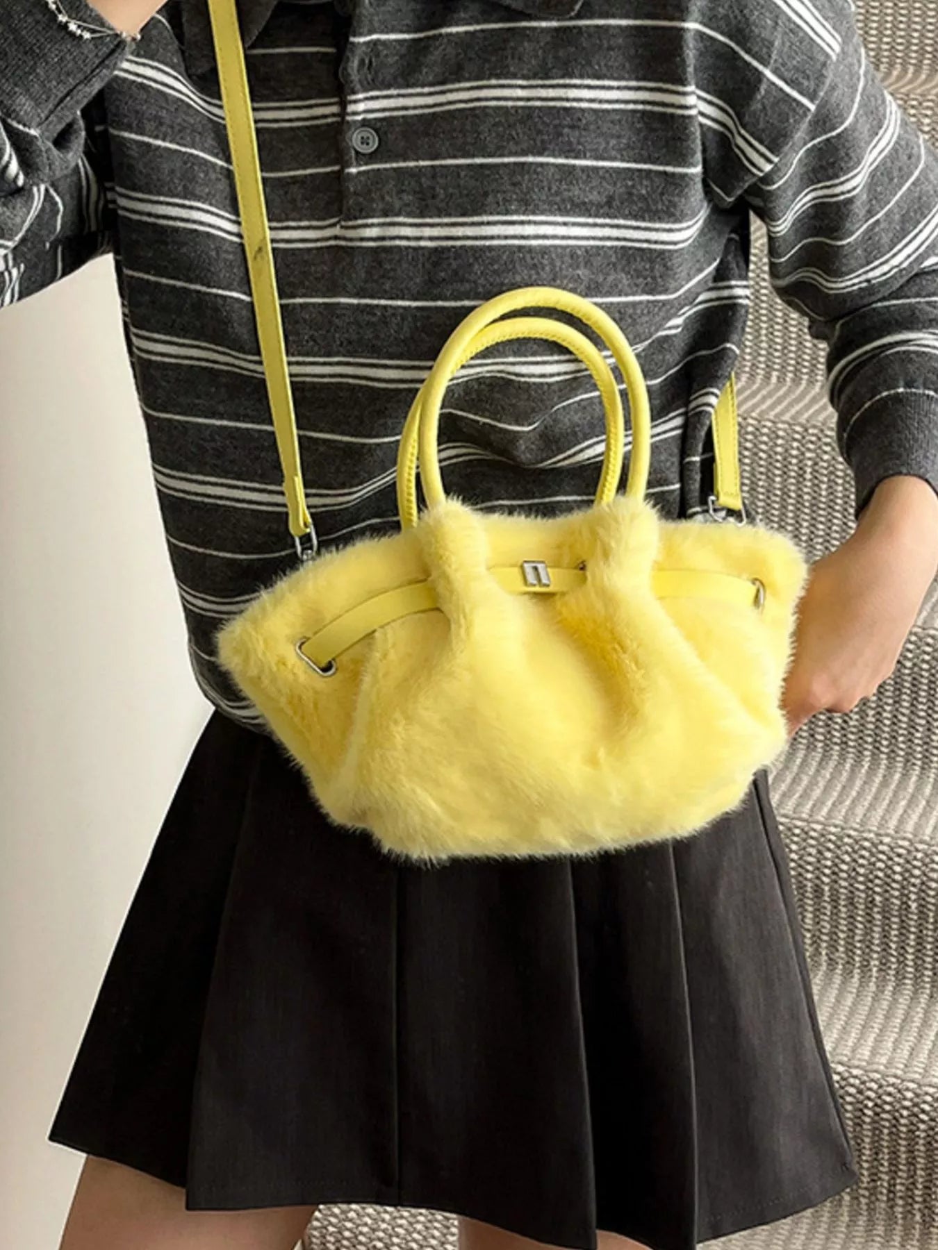 Person holding a yellow fluffy handbag with a striped shirt and black skirt.