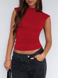 Person wearing a red sleeveless top and black jeans against a white background