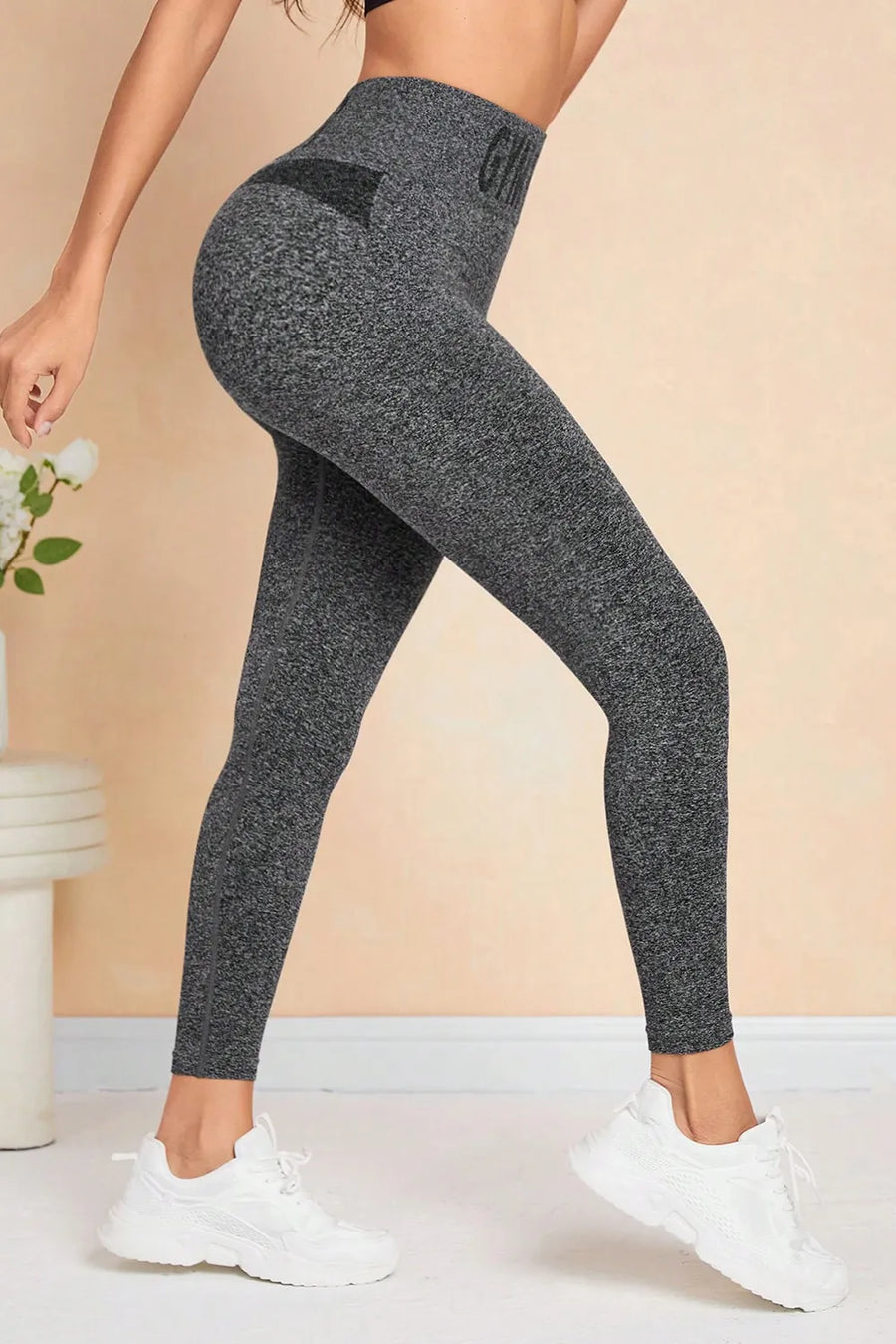 Person wearing dark gray leggings with a beige background