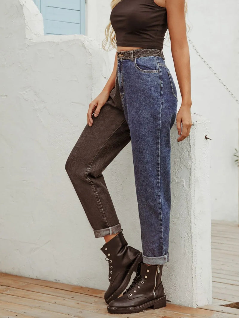 Person wearing blue jeans and brown boots against a white wall.