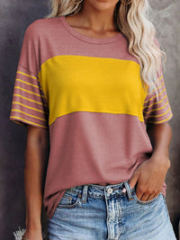 Person wearing a two-tone shirt with yellow and purple colors against a neutral background