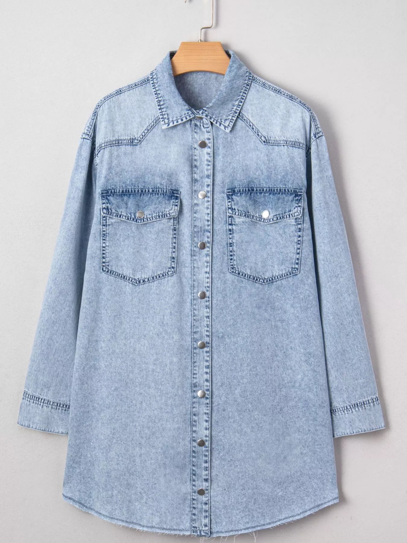 Light blue denim shirt on a hanger against a white background