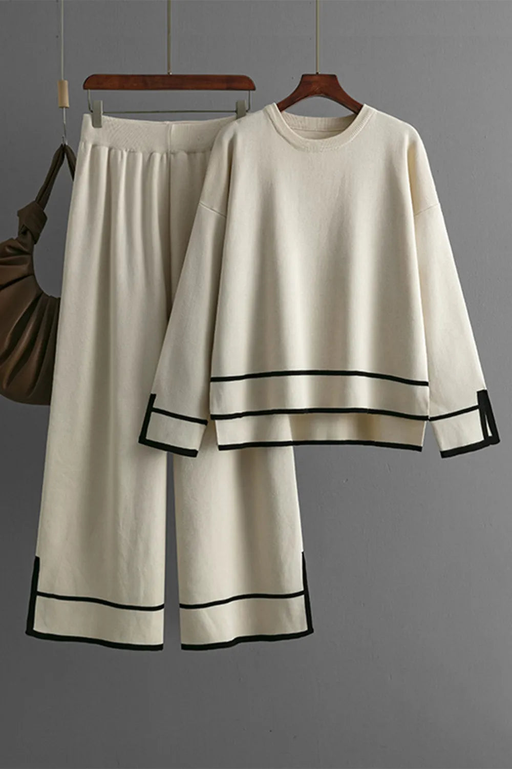 White outfit with black trim on a hanger against a gray background