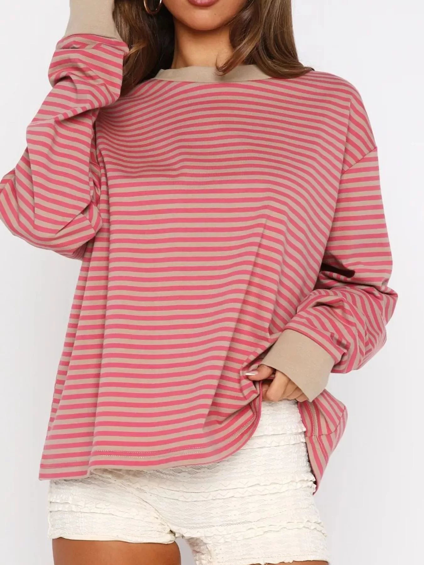 Person wearing a pink and red striped long-sleeve top on a white background