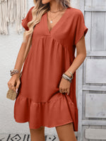 Woman wearing a rust-colored dress with a neutral background