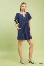 Woman wearing a navy dress with white trim on a light green background