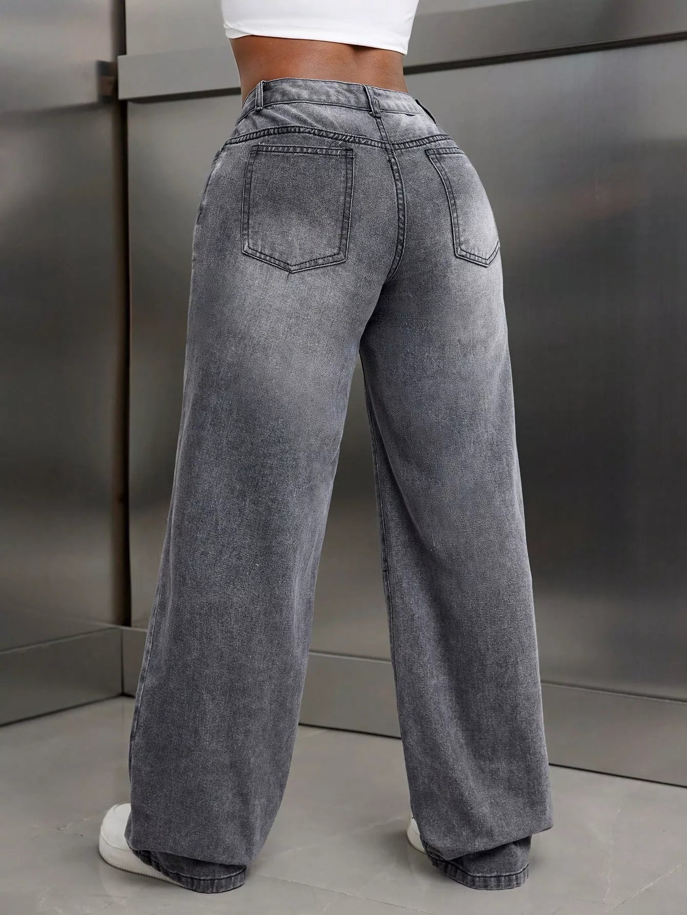 Person wearing high-waisted gray jeans against a neutral background