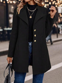 Person wearing a black coat with gold buttons on a street at night.