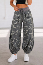 Camouflage pants worn by a person on a plain background