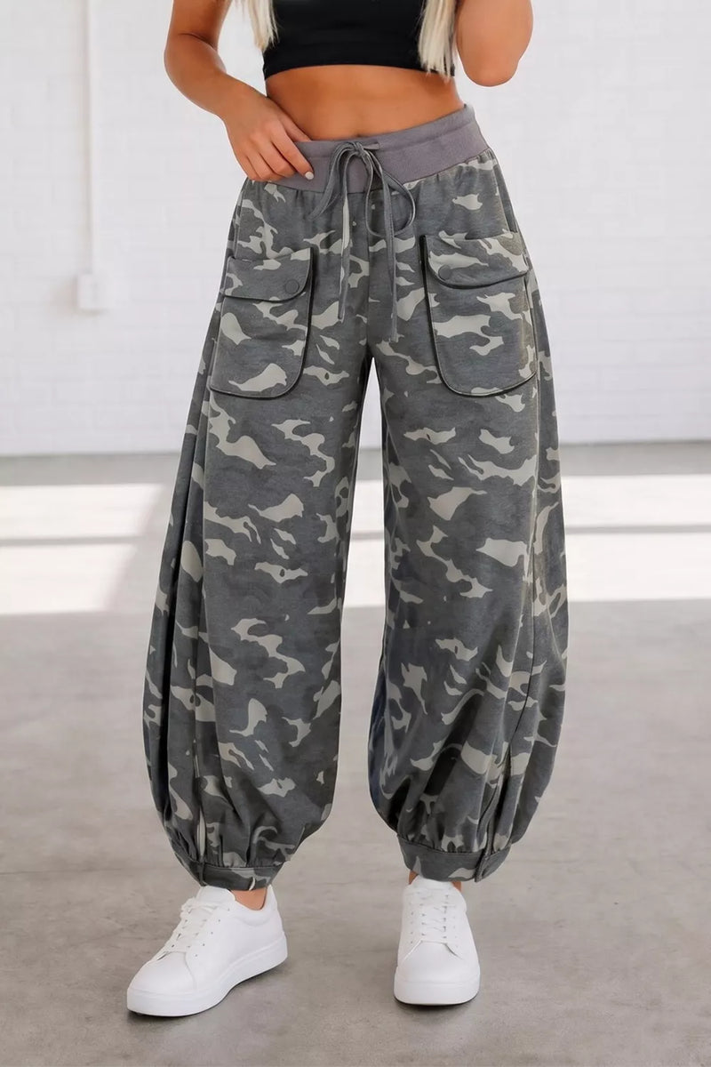 Camouflage pants worn by a person on a plain background
