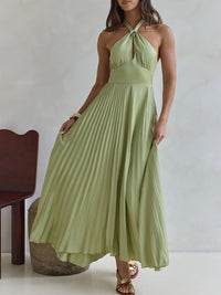 Woman wearing a light green halter neck dress against a plain background