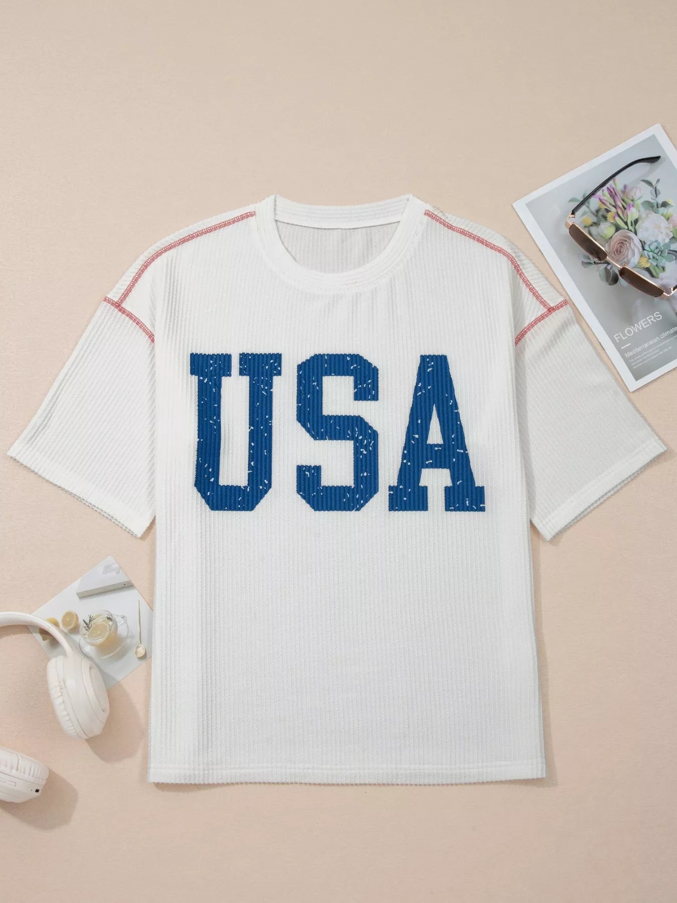 White t-shirt with 'USA' printed in blue on a beige background