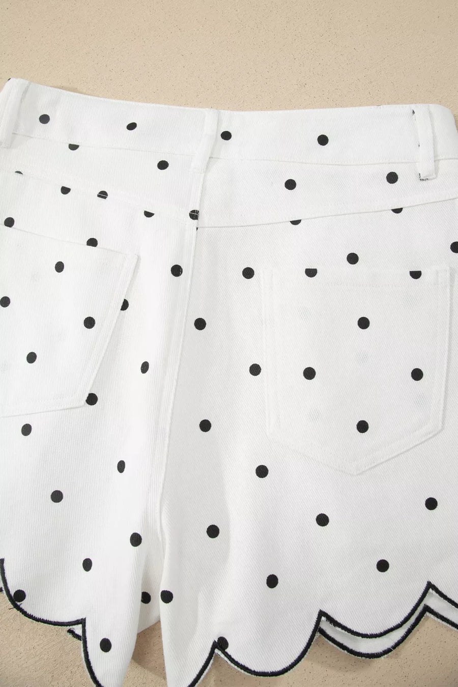 White shorts with black polka dot pattern on a beige background