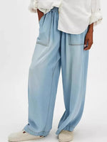 Light blue wide-leg jeans worn with a white shirt on a light gray background