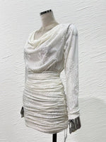 An off-white ruched mini dress with a draped cowl neckline and long sheer sleeves featuring white floral embroidery, displayed on a mannequin against a textured white wall.
