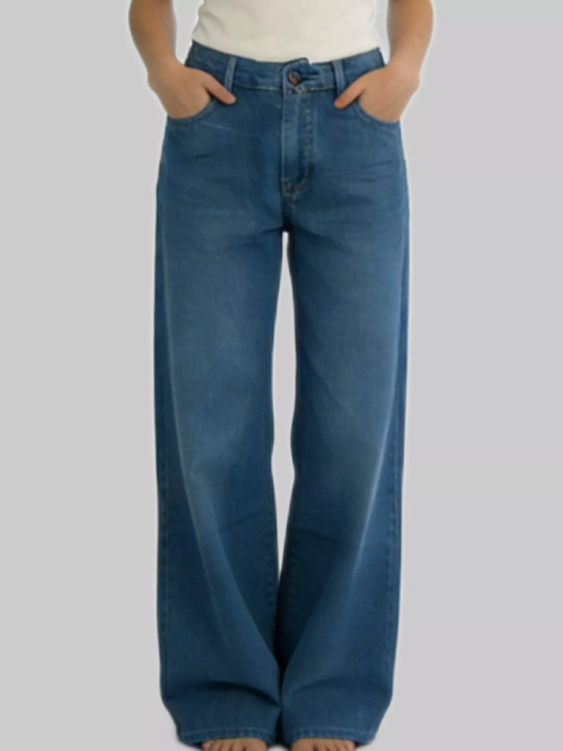 Person wearing blue wide-leg jeans on a plain background