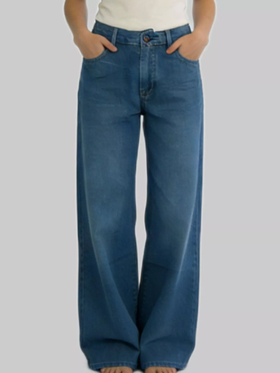 Person wearing blue wide-leg jeans on a plain background