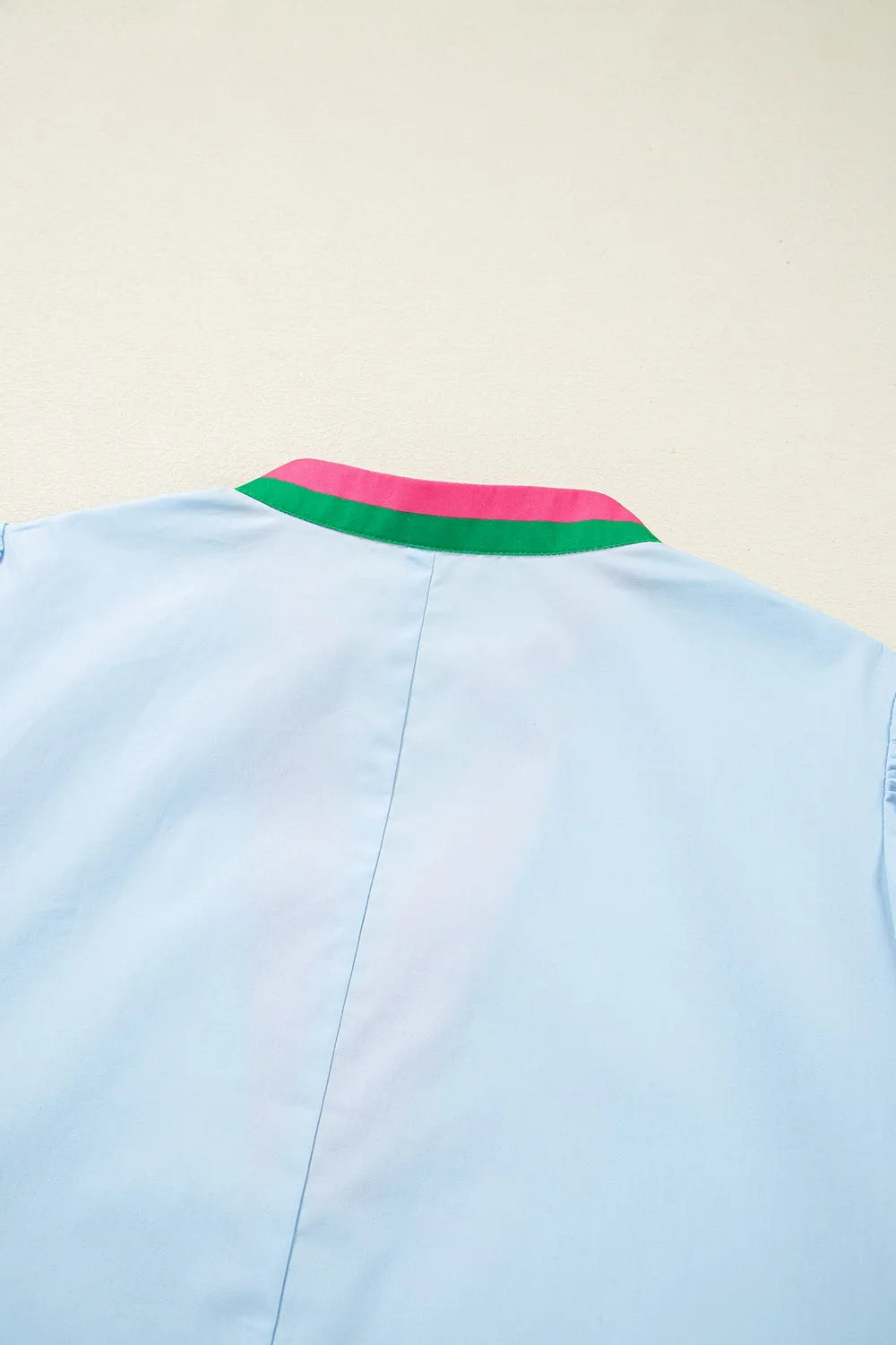 Light blue shirt with a colorful collar on a beige background