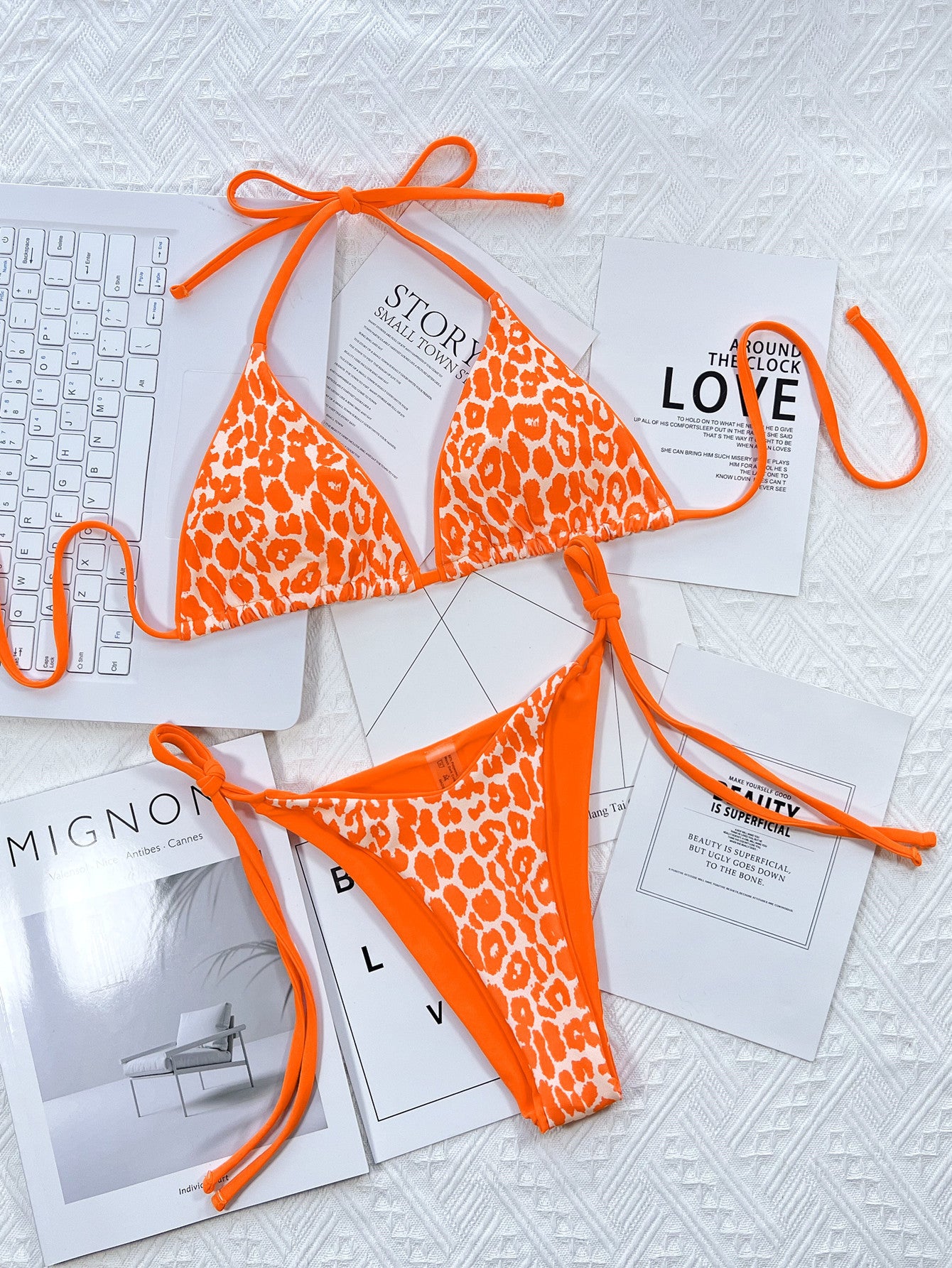 Orange leopard print bikini set on a white surface with magazines underneath