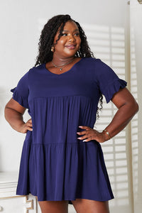Woman wearing a blue dress with ruffled sleeves against a white background