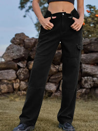 Person wearing black cargo pants standing in front of a stone wall.