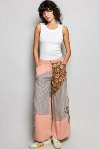 Woman wearing a white sleeveless top and a long, patterned skirt on a plain background
