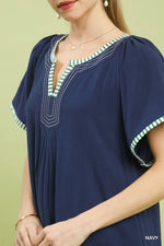 Navy blue dress with green and white trim on a light green background