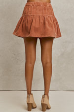 Coral corduroy skirt worn by a person on a neutral background