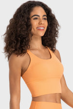 Woman wearing an orange sports bra and leggings on a white background