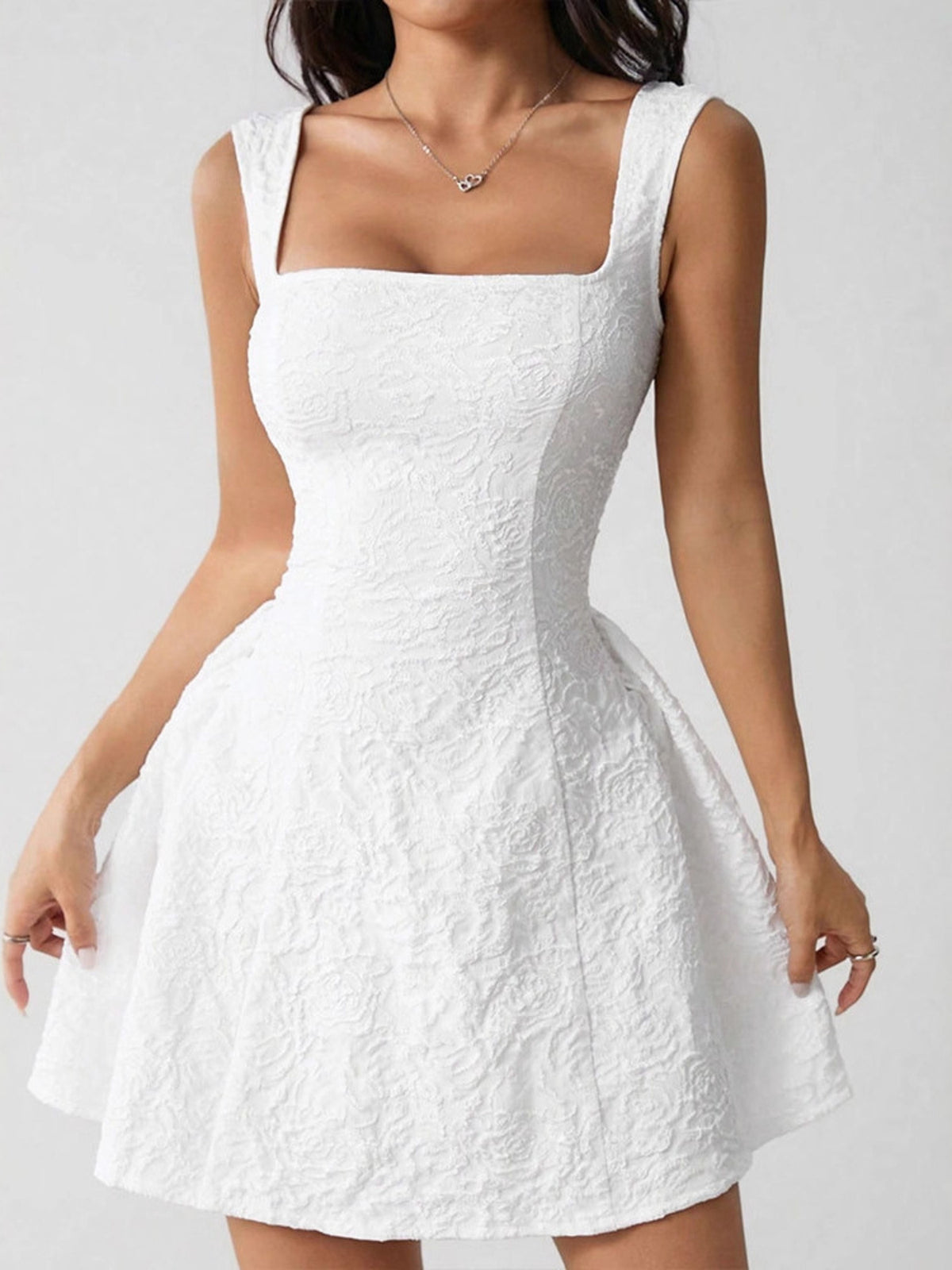 White lace dress worn by a person on a plain background