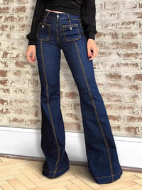 Person wearing blue flared jeans against a brick wall.