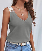 Woman wearing a gray tank top with white lace trim and blue jeans against a light background