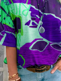 Person wearing a colorful patterned shirt with a pendant necklace.