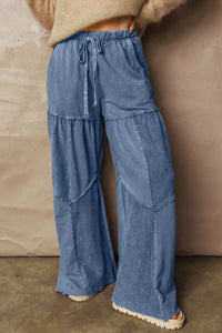 Blue tiered pants worn by a person against a beige wall.