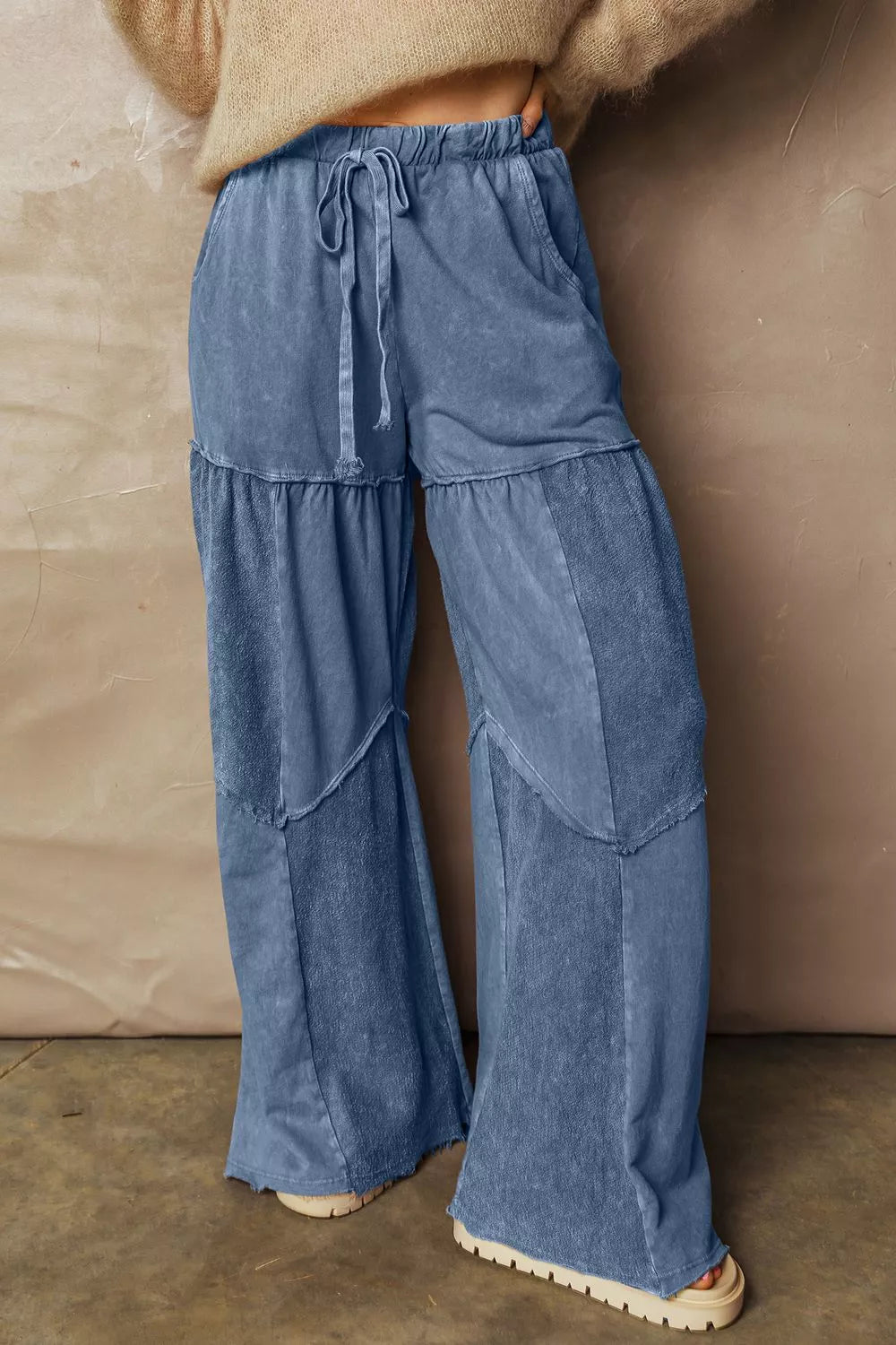 Blue tiered pants worn by a person against a beige wall.