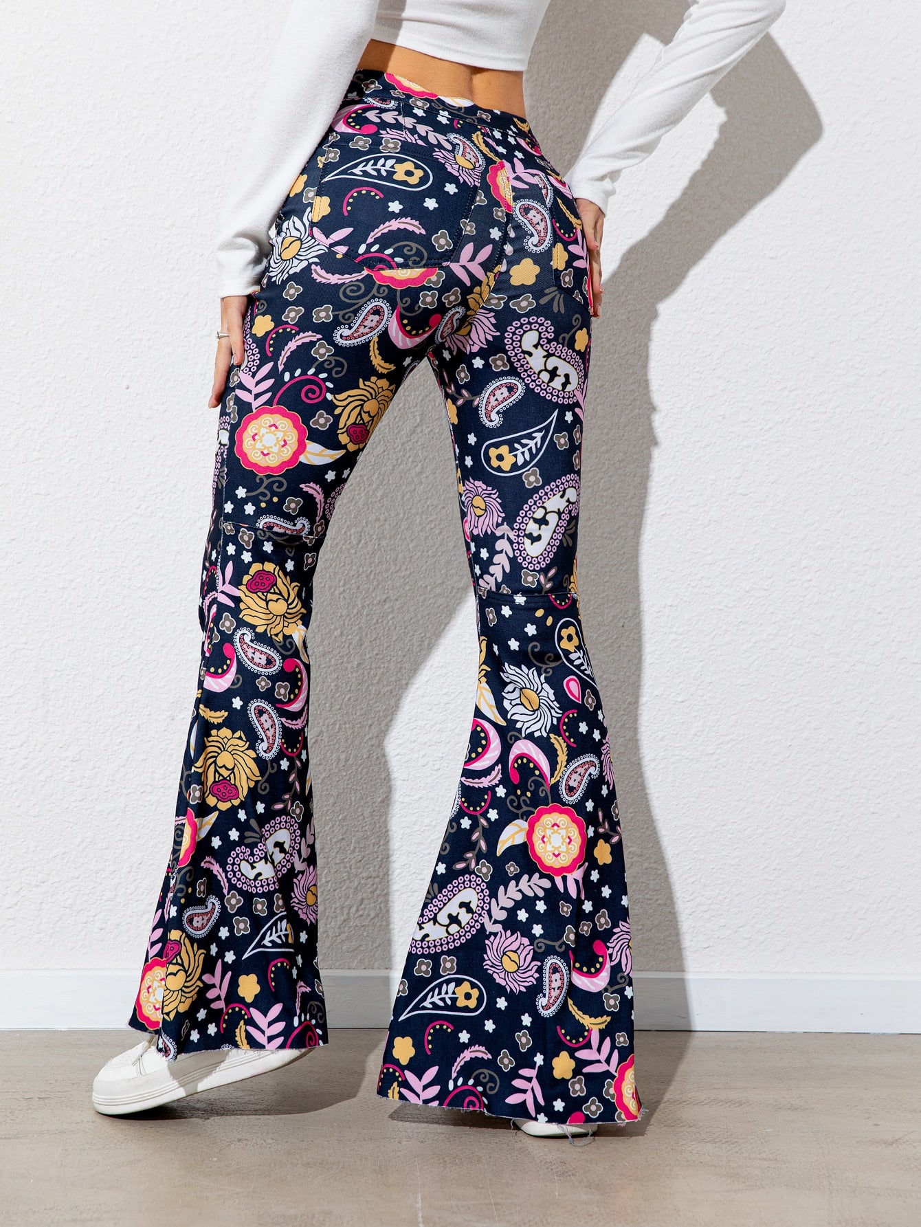 Flared pants with colorful pattern worn by a person on a plain background