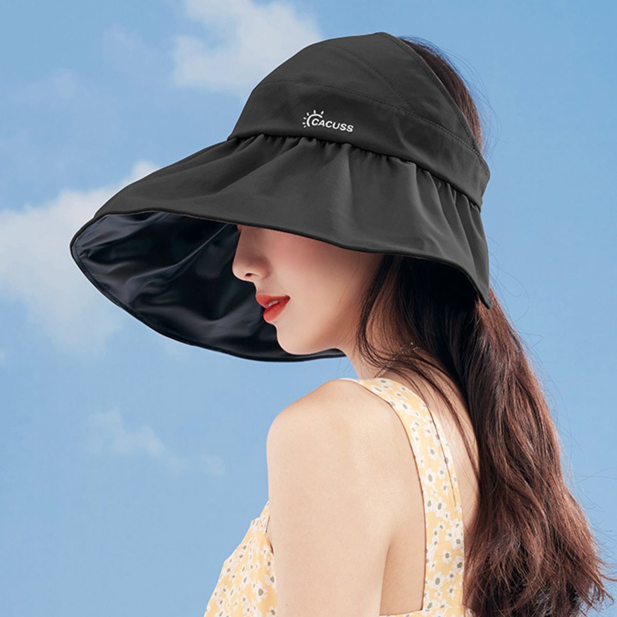 Woman wearing a black sun visor hat against a blue sky.