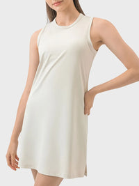 Woman wearing a white sleeveless dress on a plain background