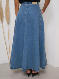 Person wearing a long blue denim skirt with a white background